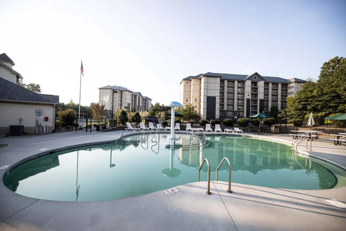 This exterior image features a vibrant swimming pool surrounded by lounge chairs and lush greenery, with resort buildings visible in the background. The scene is lively and inviting, suggesting a fun, family-friendly environment with plenty of opportunities for relaxation, play, and socializing.