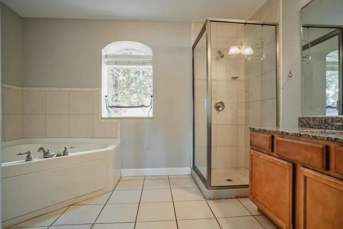 A tranquil, spa-like bathroom with a soaking bathtub, a separate shower enclosure, and a vanity with a mirror. Soft lighting and a clean, modern design evoke the sense of a luxurious escape.